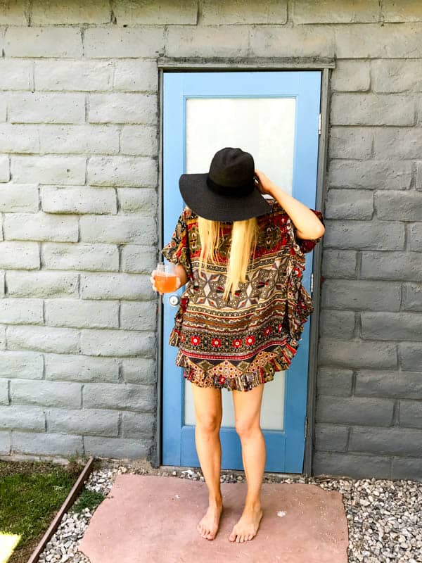 Woman in a kaftan holding a cocktail.