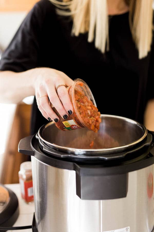 Woman adding salsa to an Instant Pot for a crunchy taco cups appetizer. 