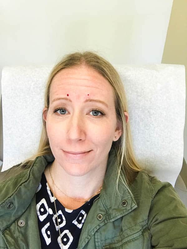 Blond woman smiling after getting Botox in her forehead.