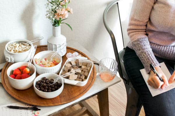 woman making notes about wine on a page next to bowls with candy.