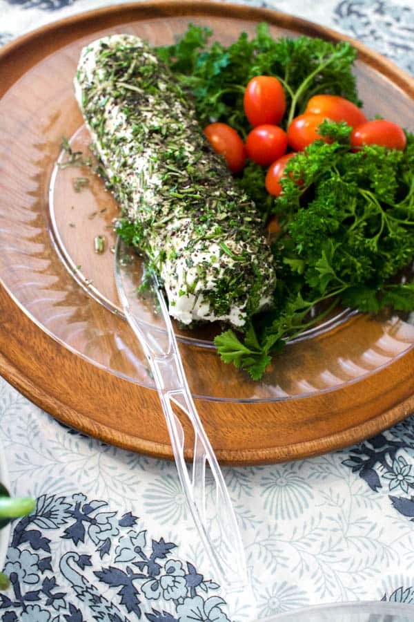 Goat cheese log with fresh herbs on a plate.