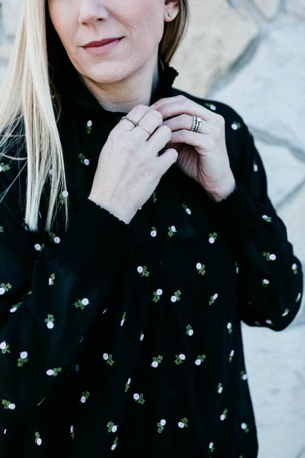 Close up of a blond girl buttoning a blouse.