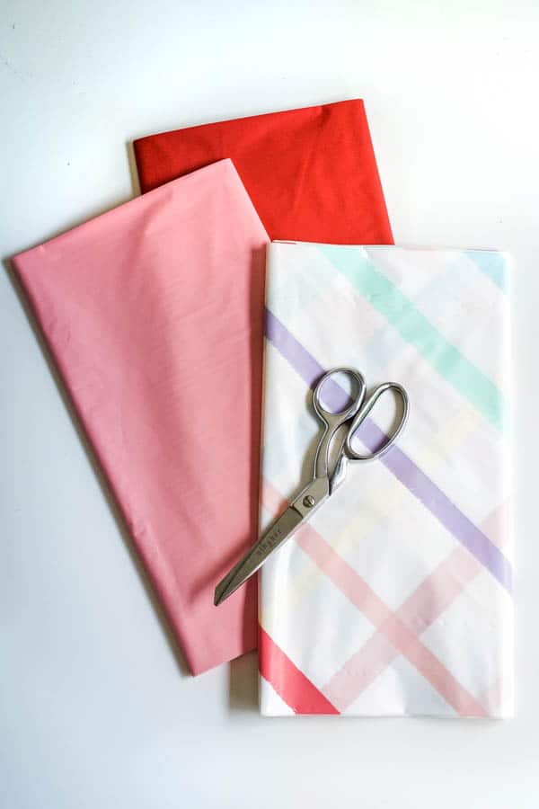 Plastic tablecloths on a table with scissors sitting on top of it to make plastic tablecloth streamers.