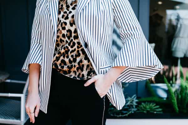 Girl with bell sleeve jacket with hand in pants pocket.