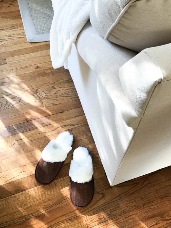 Cozy slippers on the floor next to a couch and self care ideas for moms.