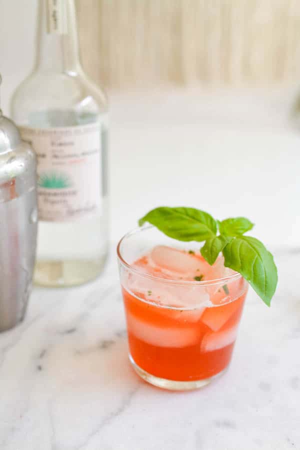 strawberry basil margarita on a table with a sprig of basil for garnish