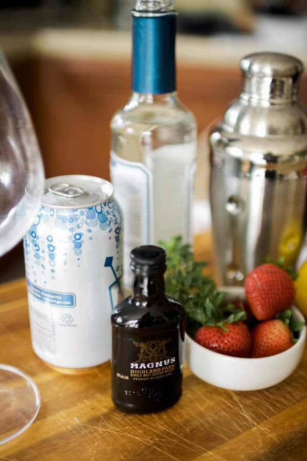 Ingredients for a strawberry whiskey sour on a wooden cutting board.