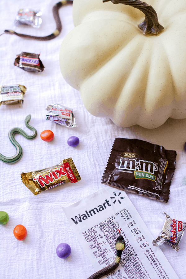 Fun-sized candy bars on a table next to a Walmart receipt and a rubber snake. 