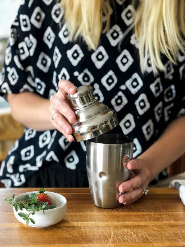 Woman putting the lid on a cocktail shaker.