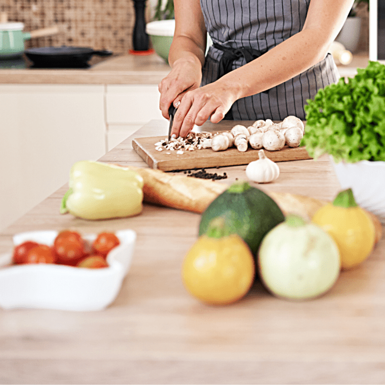 A woman cutting vegetables on a cutting board for dinner prep.