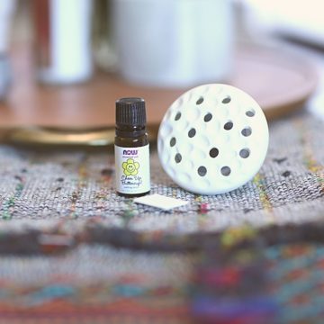 A pluggable wall diffuser laying on the table next to a bottle of essential oil.