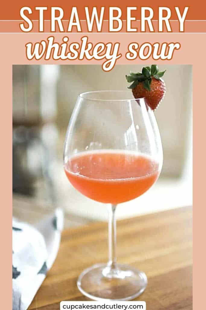 Text - Strawberry Whiskey Sour with a wine glass holding a strawberry whiskey cocktail with a strawberry garnish.