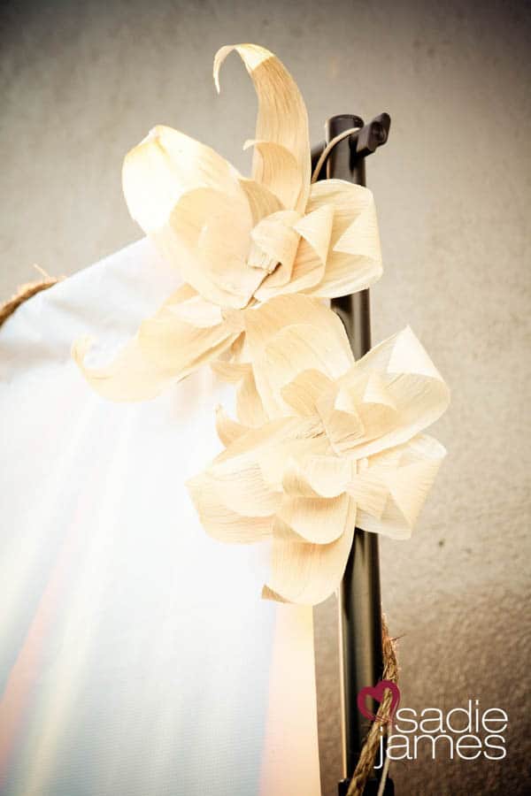 A flower made from corn husks attached to the top of an outdoor movie screen.