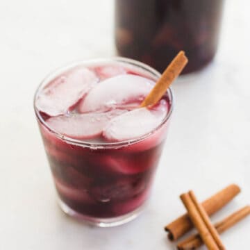 Close up of apple sangria in a cut with ice and a cinnamon stick.
