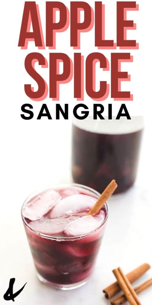 A glass with ice and apple sangria with a cinnamon stick sticking out.