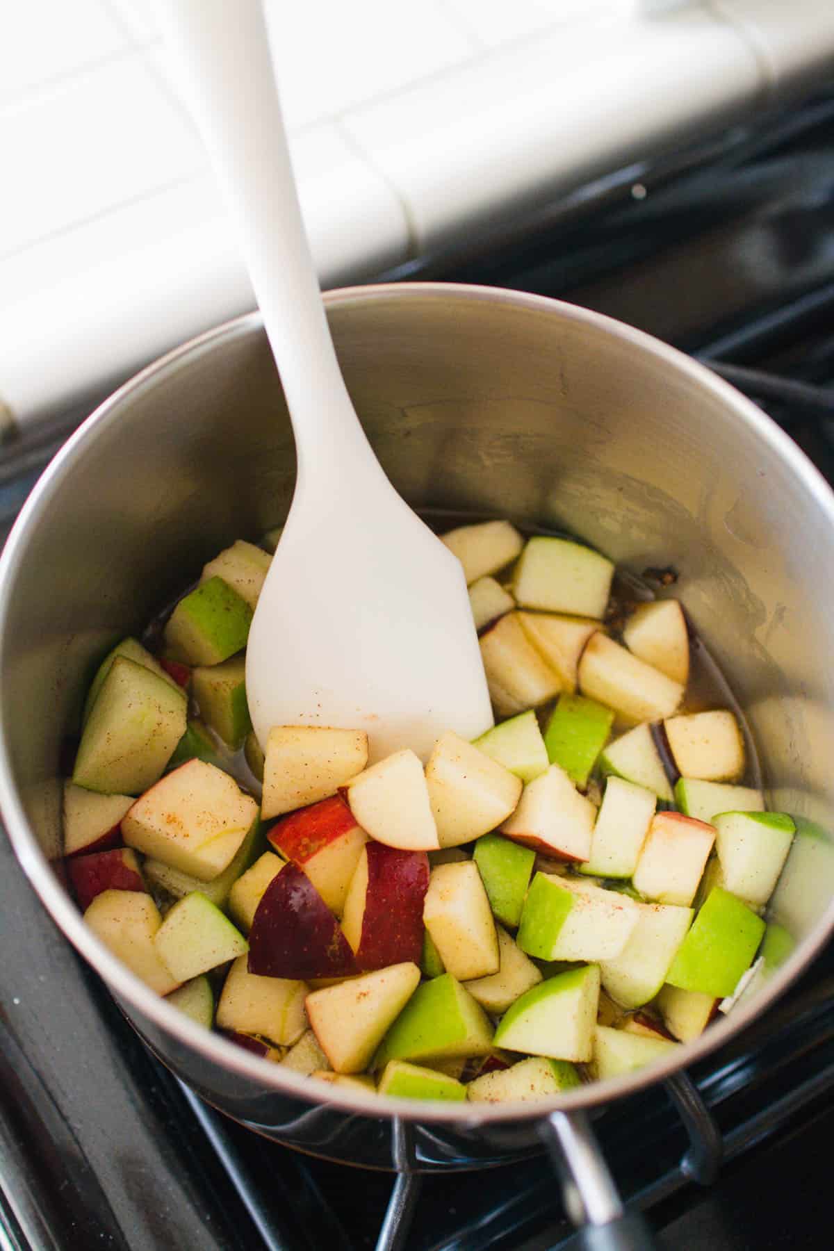 Saucepan with chopped apples and white spatula.