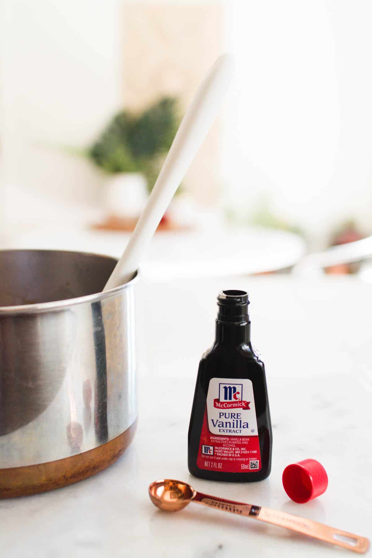 A bottle of vanilla on a counter next to a saucepan.