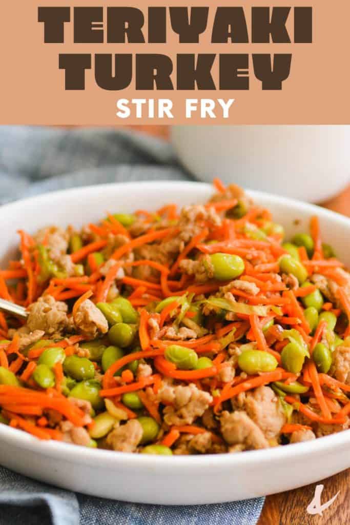 A bowl with ground turkey, shredded carrots and edamame in a bowl tossed with teriyaki sauce.
