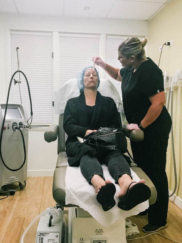Tannaz at Cosmeticare putting numbing cream on a woman's face prior to a CO2 laser resurfacing.