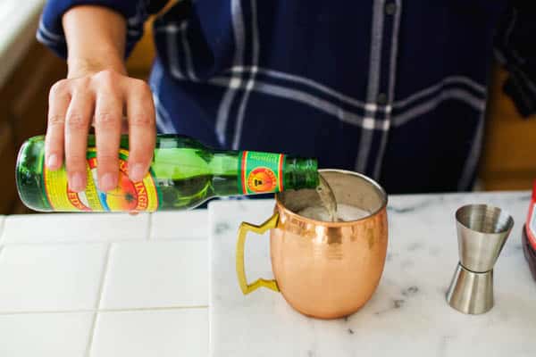 Ginger beer being poured into a copper mug.