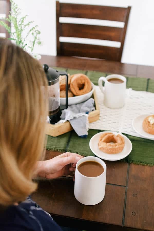 A woman sitting at a table enjoying a cup of coffee.