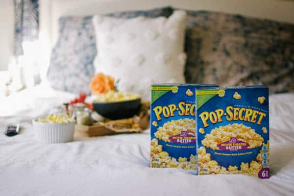 Boxes of Pop Secret microwave popcorn on a bed for a movie night.