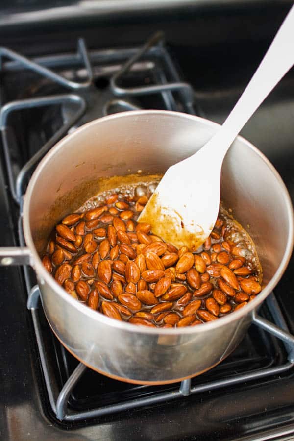 Candied almonds being stirred on the stovetop.