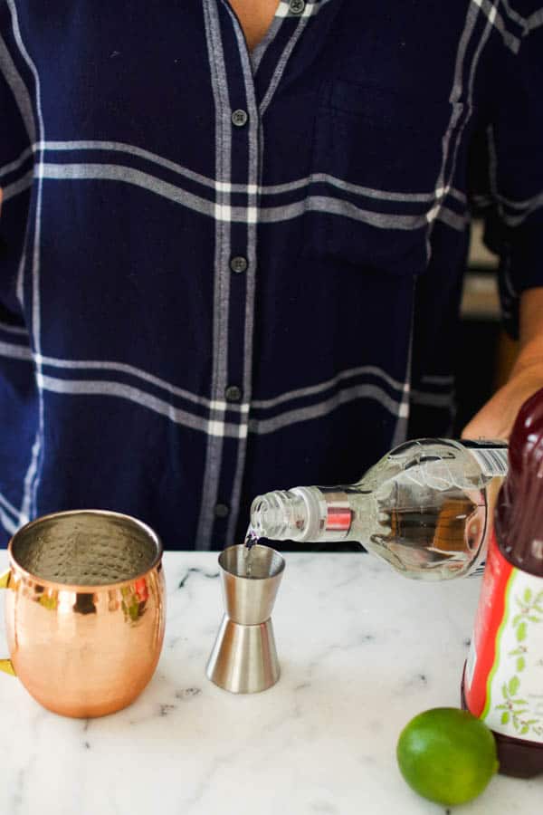 Woman adding vodka to a jigger.