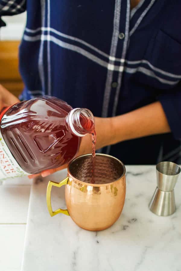 Woman pouring juice into a copper mug.