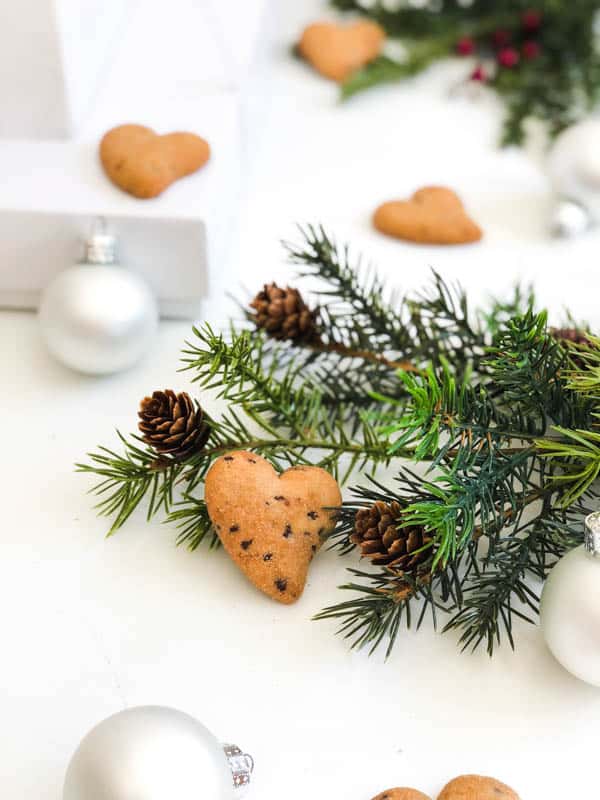 Heart shaped Mulino Bainco Cuoricini cookies next to a pine branch and ornament for holiday gift idea.