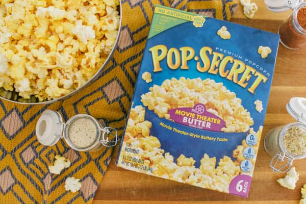 Overhead photo of a box of Pop Secret popcorn next to a bowl of popped popcorn and jars of seasonings. 