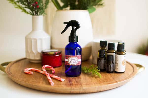 A small blue glass spray bottle on a tray on a table next to essential oils. 