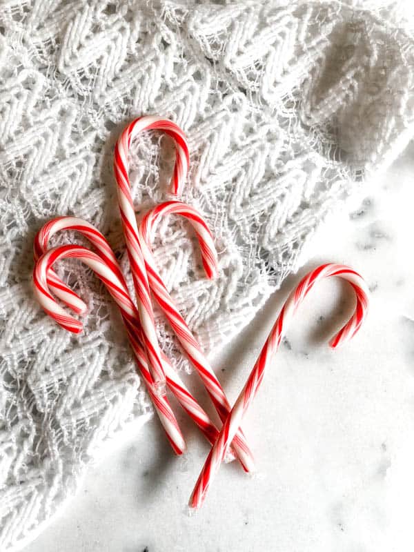 Candy Canes on top of a piece of lace on a table.
