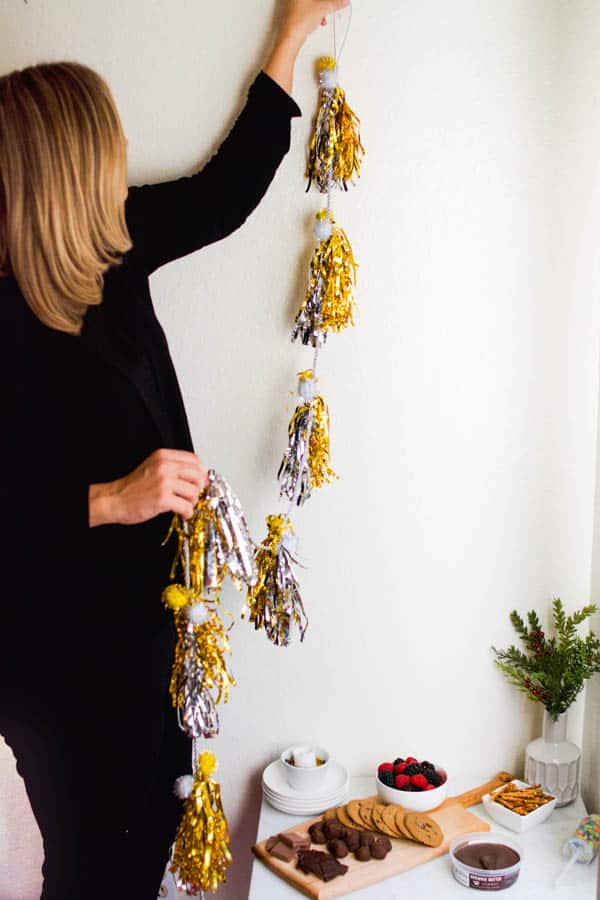 Woman putting up a metallic garland for a New Year's Eve Party. 