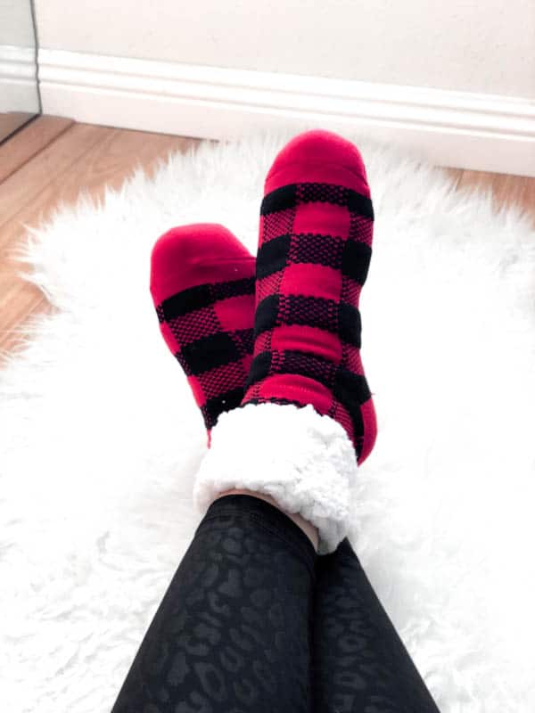 Woman wearing fuzzy socks on a fur rug.