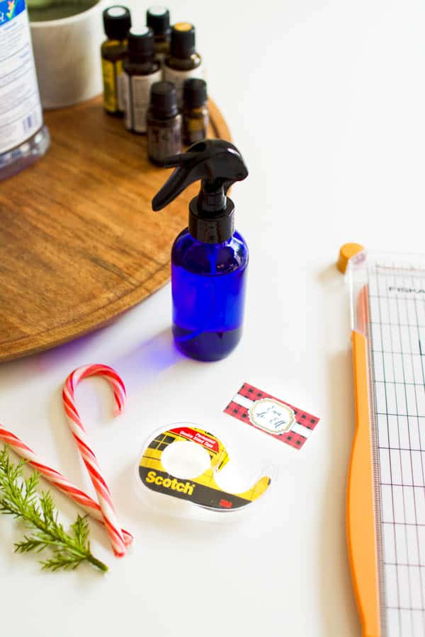 Tape and a paper cutter on a table next to a blue glass spray bottle. 