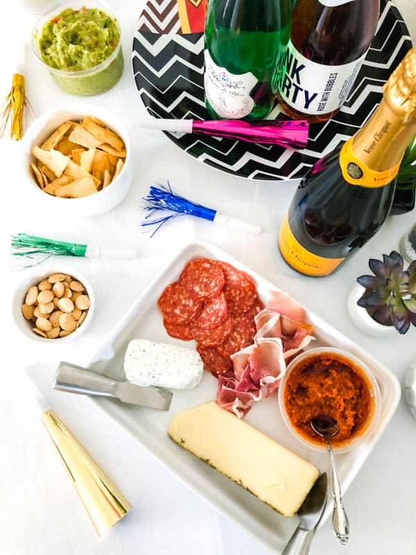 An overhead shot of a party table for New Year's Eve with champagne and a meat and cheese charcuterie.