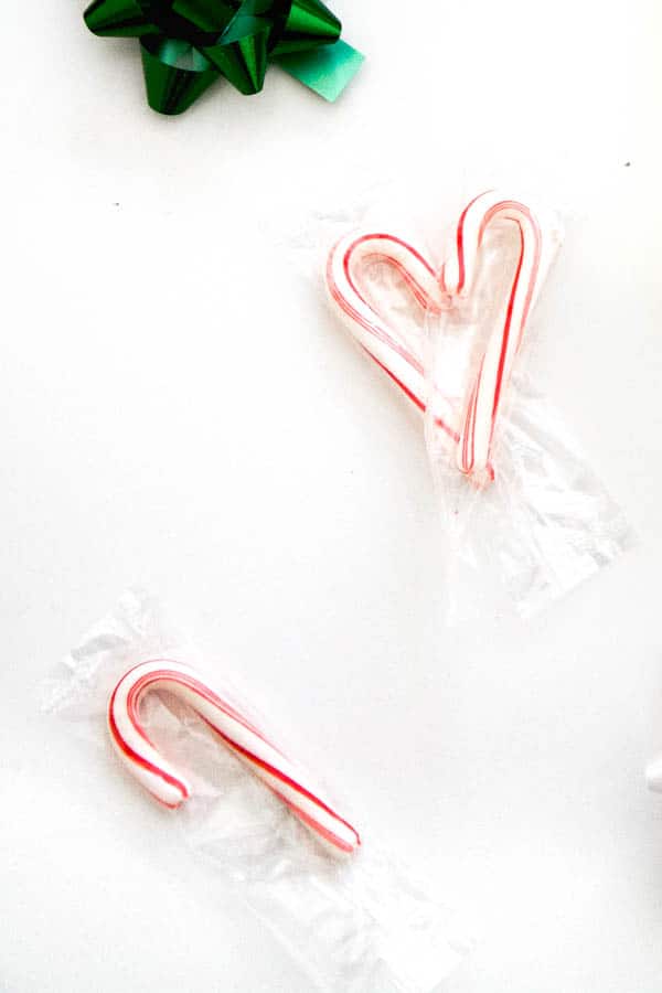 Mini candy canes laid out on a table near a green bow.