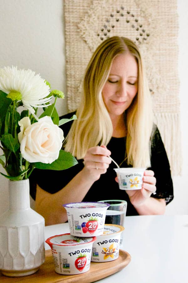 Woman sitting at a table enjoying yogurt. 
