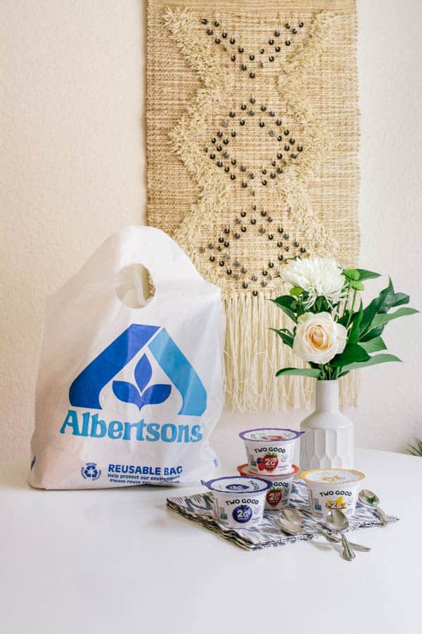 Two Good Yogurt next to Albertsons shopping bag on a kitchen table.