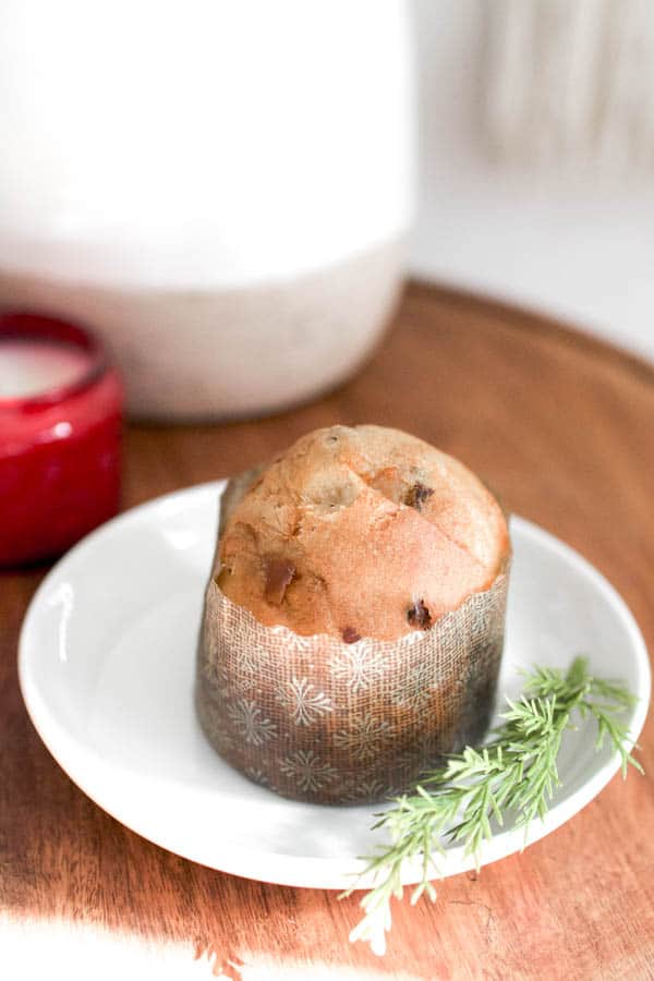 Mini panettone on a white plate with a sprig of greenery.