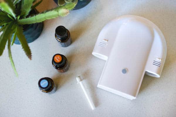 Essential oil diffuser for shower on a table next to Doterra oil bottles.