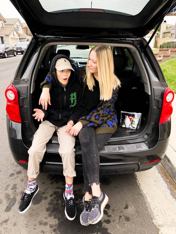 Mom and son sitting in the back of a car with a small wellness kit next to the mom.
