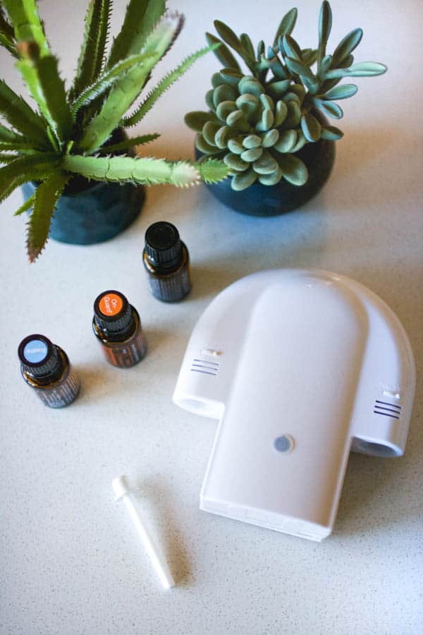 A shower diffuser laying on a table next to bottles of essential oils. 