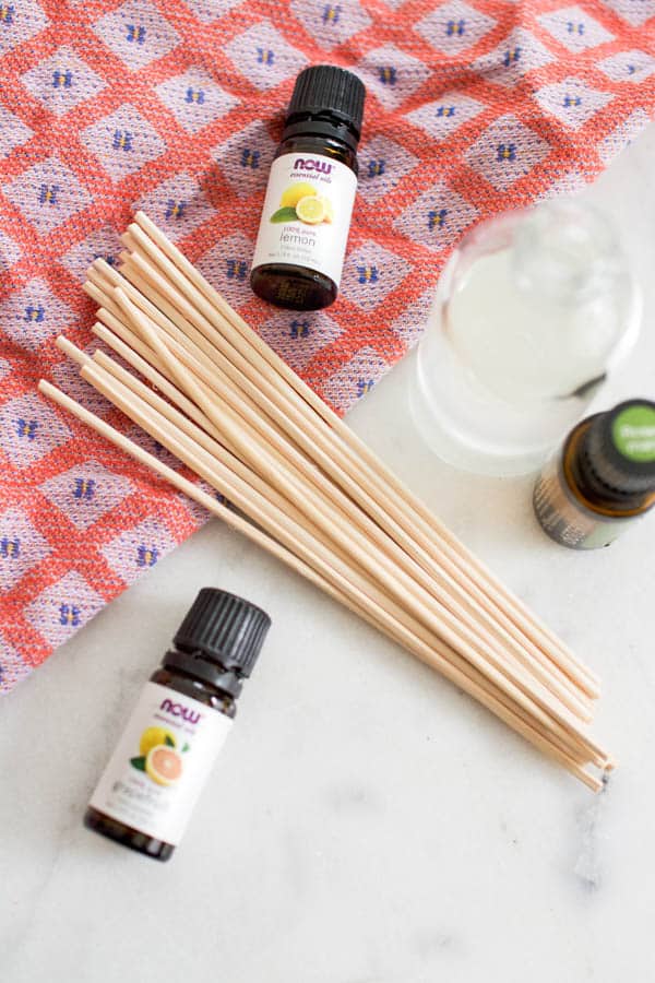 Overhead view of wooden reeds next to essential oils.