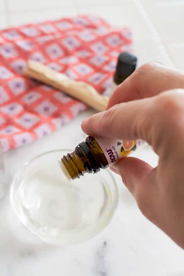 Woman adding drops of essential oils to a small bowl.