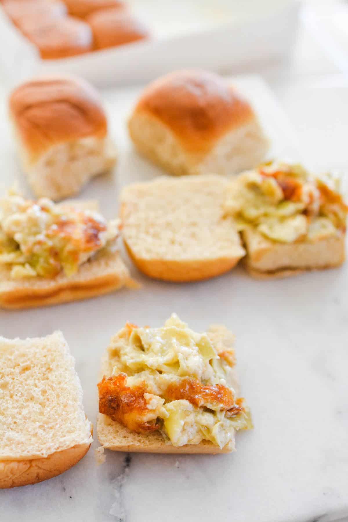 Artichoke Dip scooped onto slices of Hawaiian Rolls.