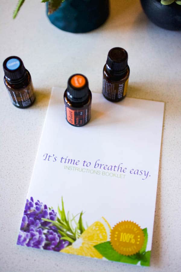 Bottles of essential oils on a table with the instruction booklet for the shower diffuser.