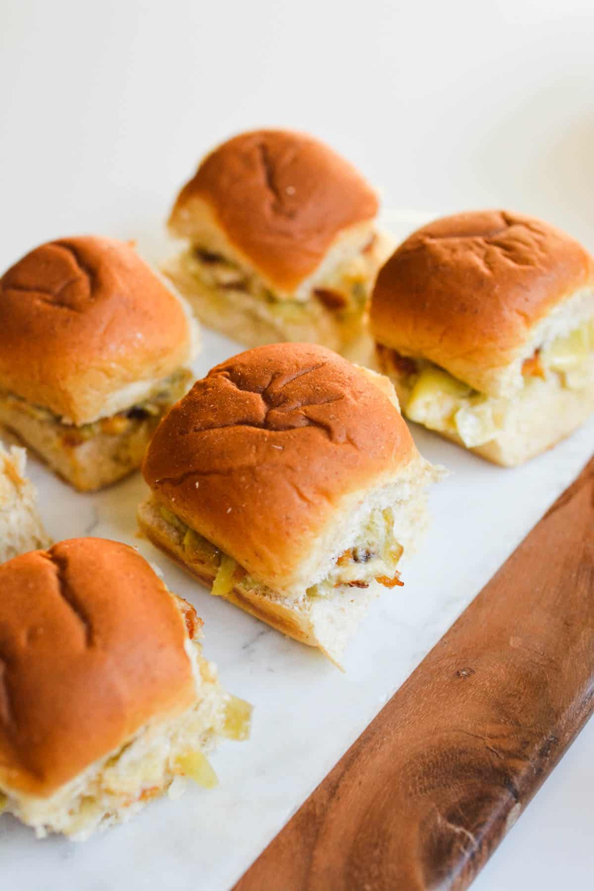 Hawaiian Rolls on a serving platter that have artichoke dip on it.