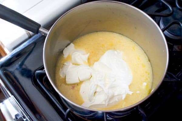 Cream cheese and cream of chicken soup in a saucepan on the stove.